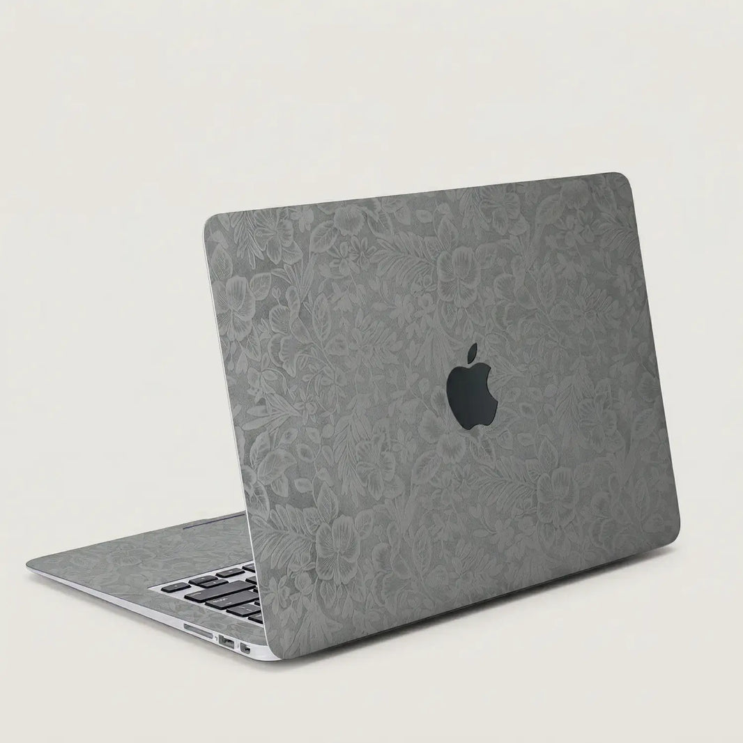 Classic gray hibiscus embossed MacBook skin on an open laptop, lid and interior view