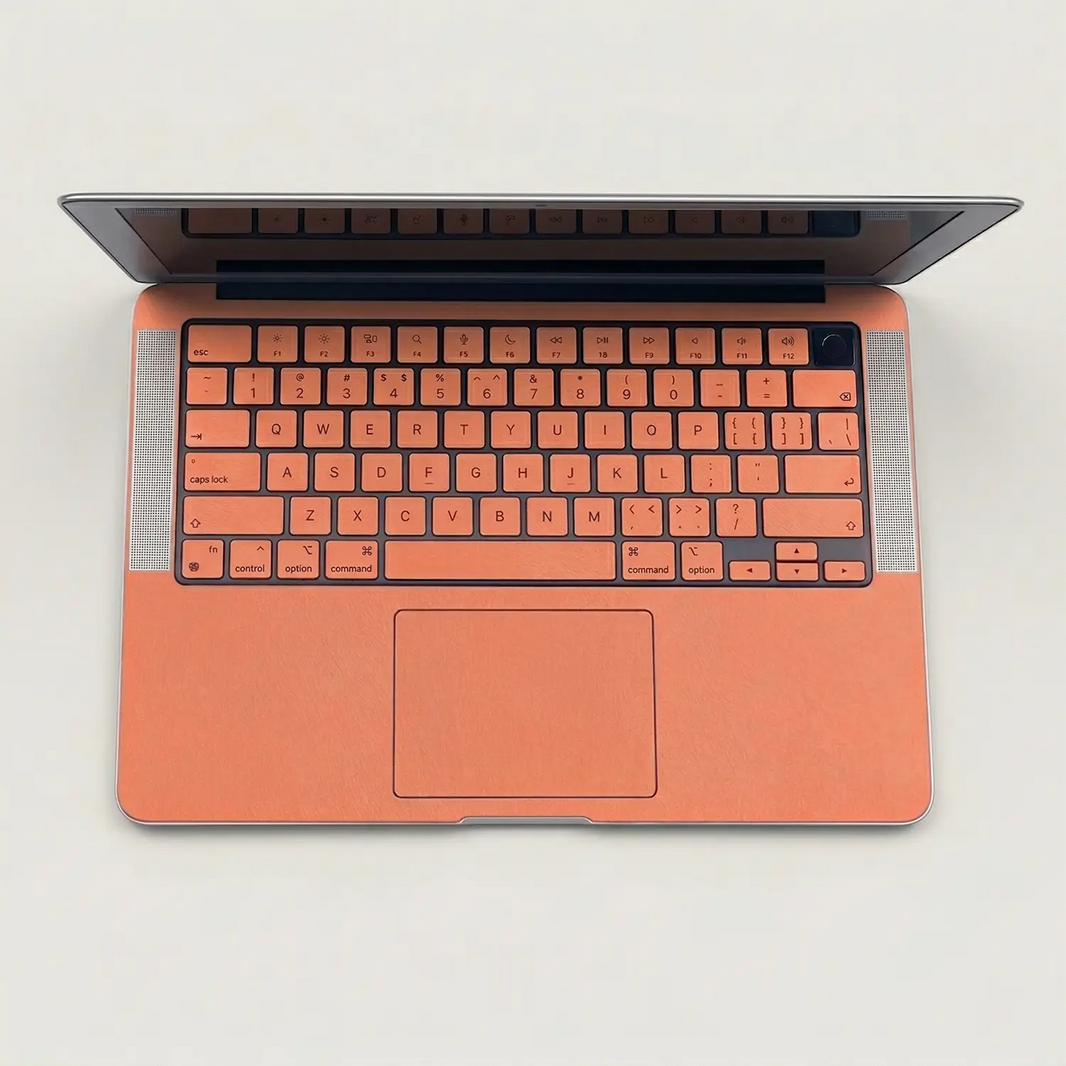 Sunset orange MacBook skin on the keyboard deck and palm rest, overhead view