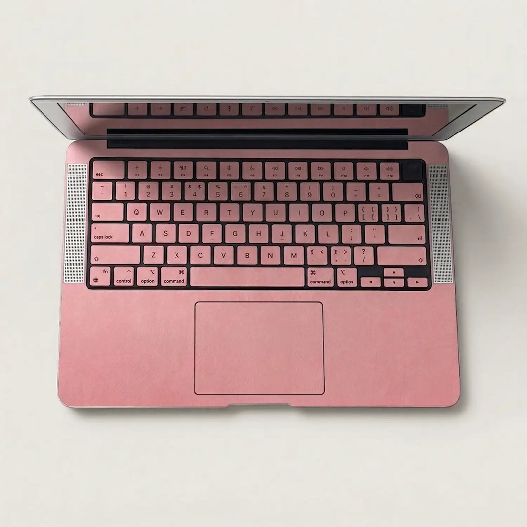 Blush pink MacBook skin on the keyboard deck and palm rest, overhead view