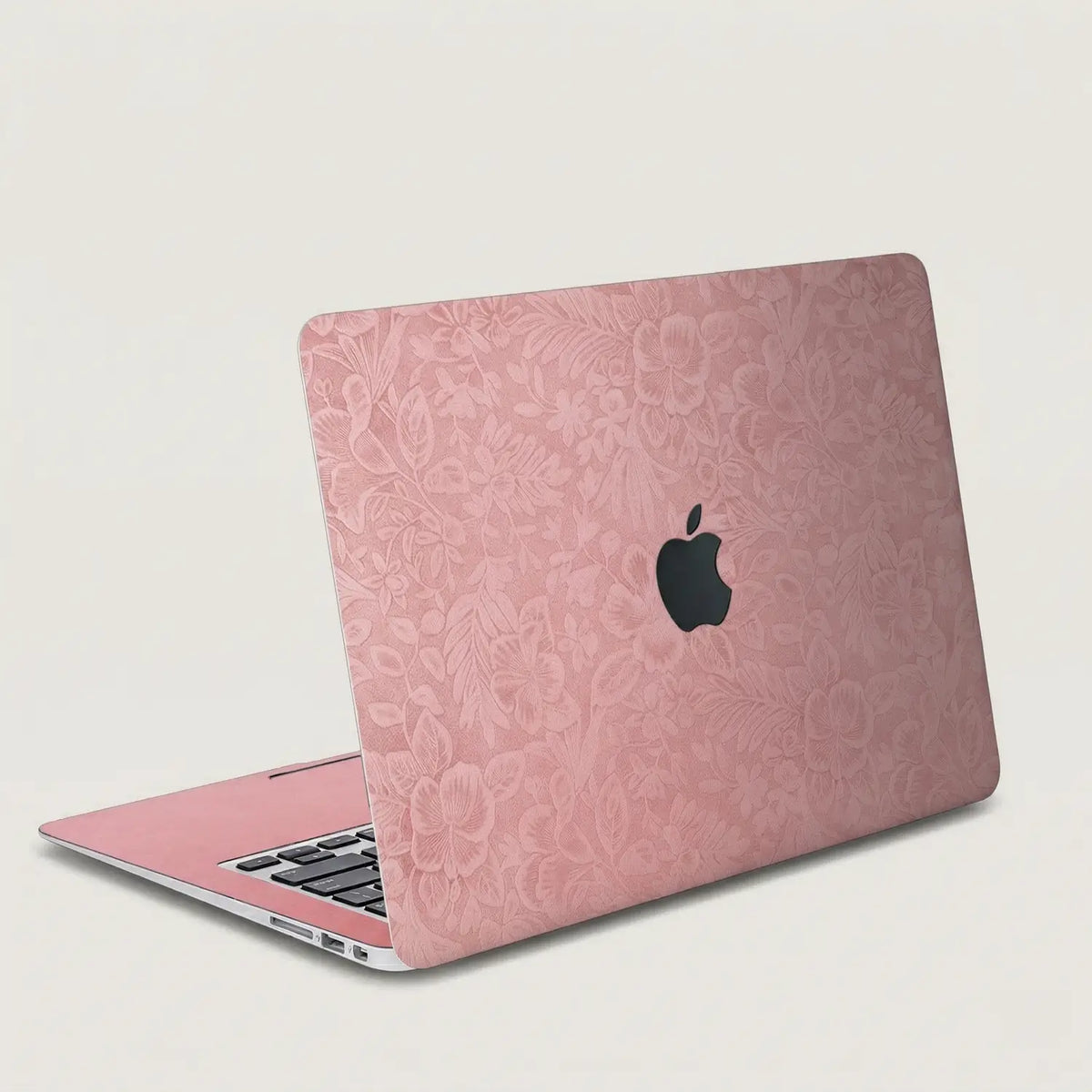 Blush pink hibiscus embossed MacBook skin on an open laptop, lid and interior view