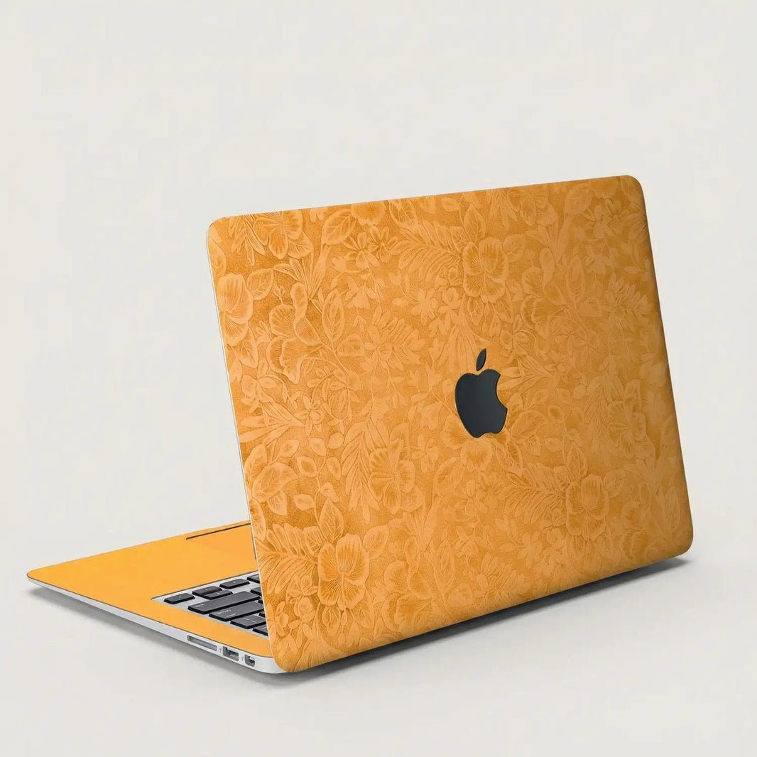 Sunny yellow hibiscus embossed MacBook skin on an open laptop, lid and interior view