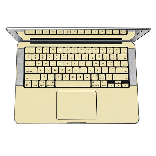 AI-assisted champagne gold MacBook skin visualisation showing the keyboard deck, trackpad, keycap stickers and covered power key. Cut layout varies by model.