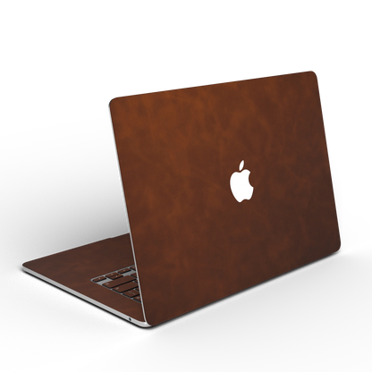 Coffee Brown scrub-textured synthetic leather MacBook skin, open rear angle material illustration. Rendered on MacBook Air 15.3 M3-M5 as shared material reference; exact cutouts and included pieces follow the selected model and coverage. Laptop not included.