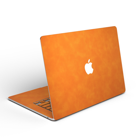 Orange scrub-textured synthetic leather MacBook skin. Open rear angle material illustration. Air 15.3 M3-M5 shared material/installation illustration; actual cutouts and included pieces follow the selected model and coverage. Laptop not included.